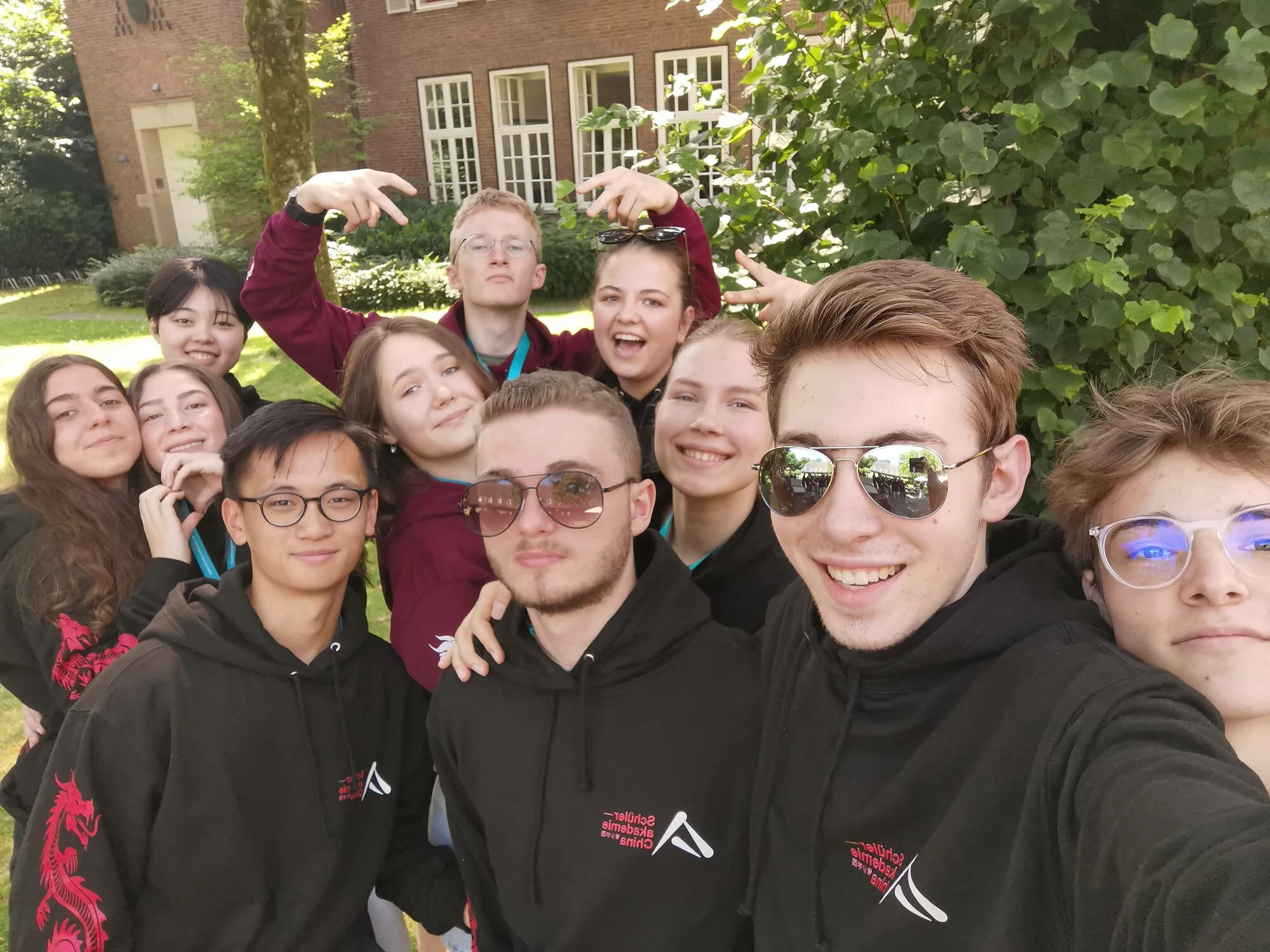 Eine Gruppe von Jugendlichen posiert für die Kamera. Alle tragen den gleichen schwarzen Pullover mit dem Logo der Akademie.